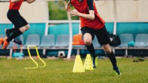 Boy Soccer Player In Training. Boys Running Between Cones amd Jumping During Practice in Field on Sunny Day. Young Soccer Players at Speed and Agility Practice Session